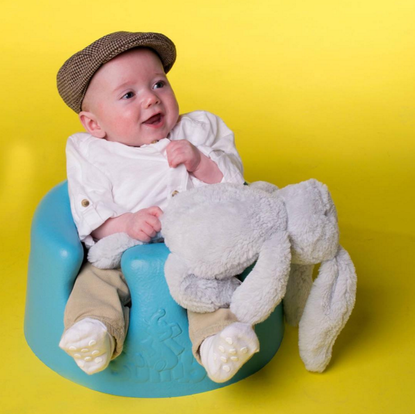 A Baby Wearing a Cap and Holding a Toy Rabbit